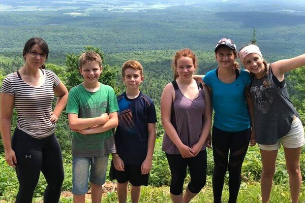 Une intervenante avec cinq jeunes prennent la pose lors d'une randonnée pédestre sur le haut d'une montage