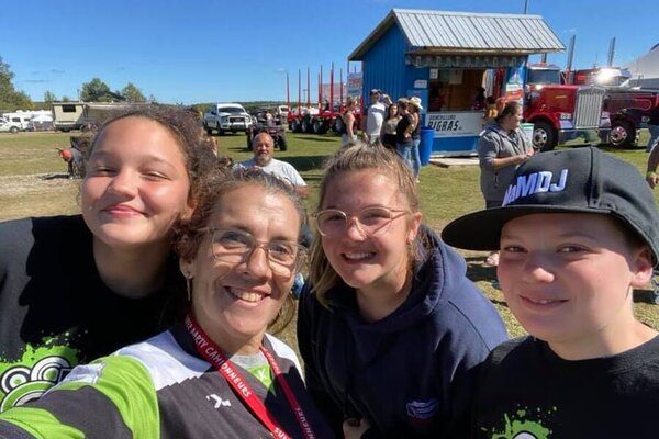 Intervenante se prend en photo avec 3 des jeunes à l'extérieur durant l'été