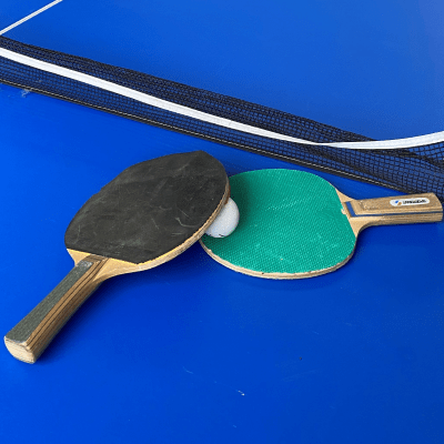 Raquettes de ping-pong sur une table bleu avec un filet