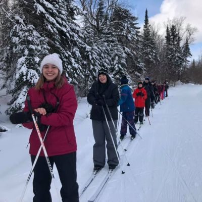 Groupe d'une dizaines de jeunes un derrière l'autre sur une piste de ski de fond
